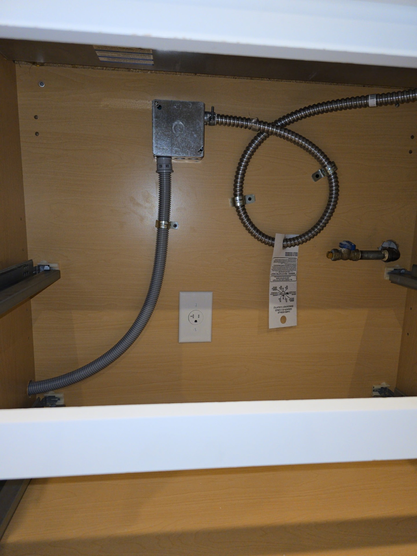 Dedicated 240V appliance outlet with flex conduit installed inside cabinetry