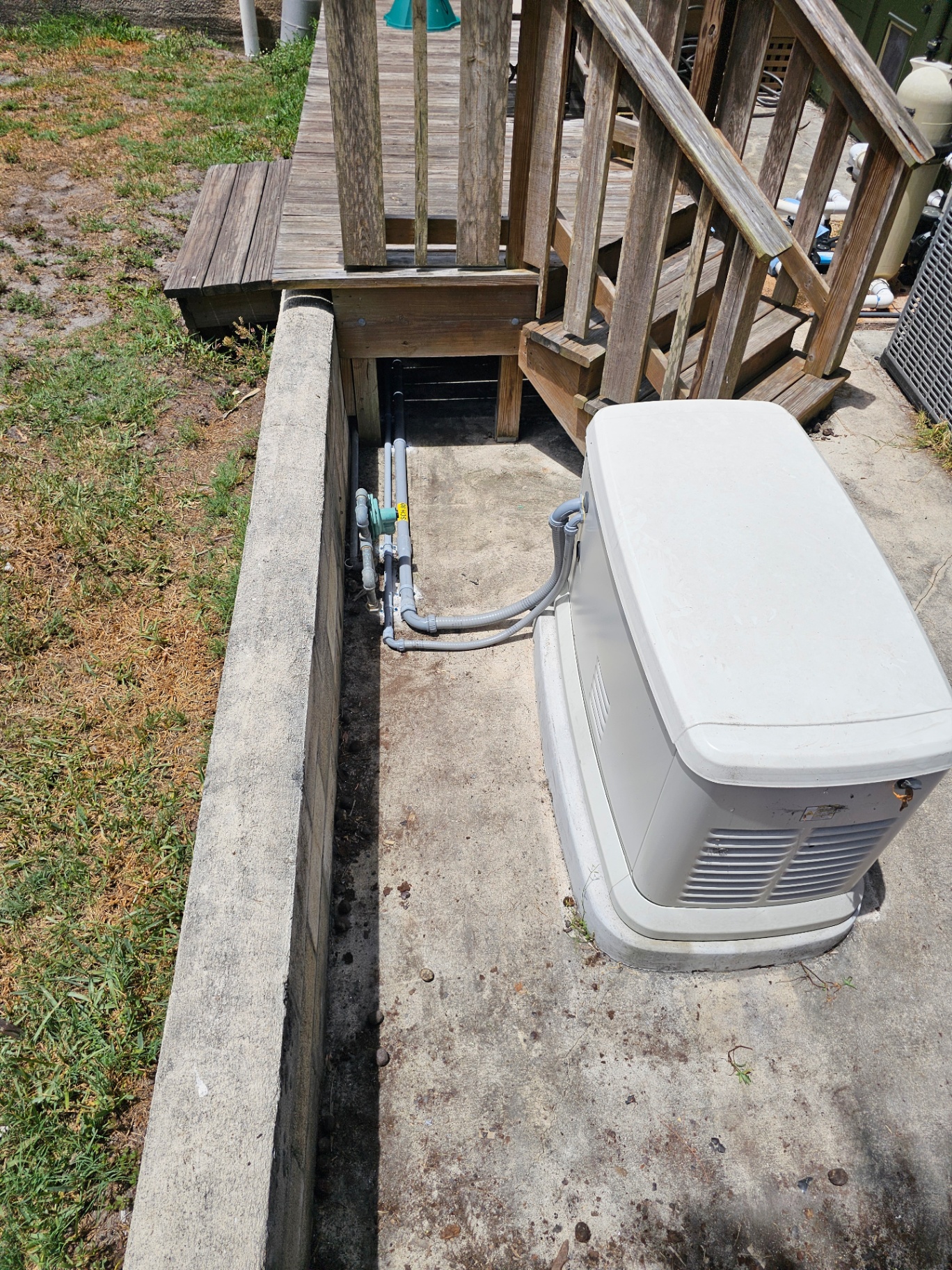 Whole-home standby generator installed beside a deck